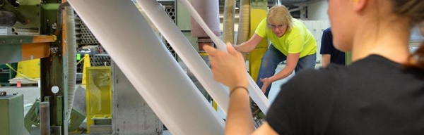 An International Paper worker monitors the process as paper rolls through a machine